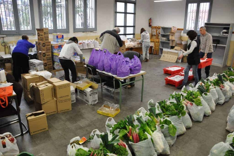 Els comerciants que col·laboren amb el projecte de distribució d'aliments preparen els lots extraordinaris de Nadal 